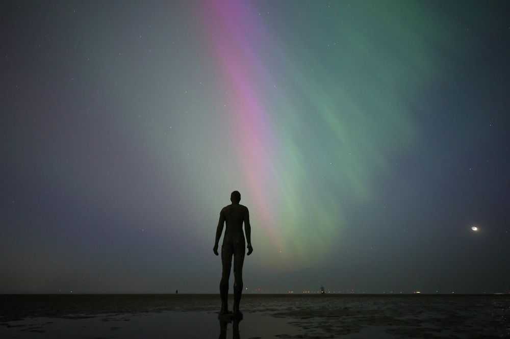 Imagen de una Aurora Boreal frente a la escultura 
