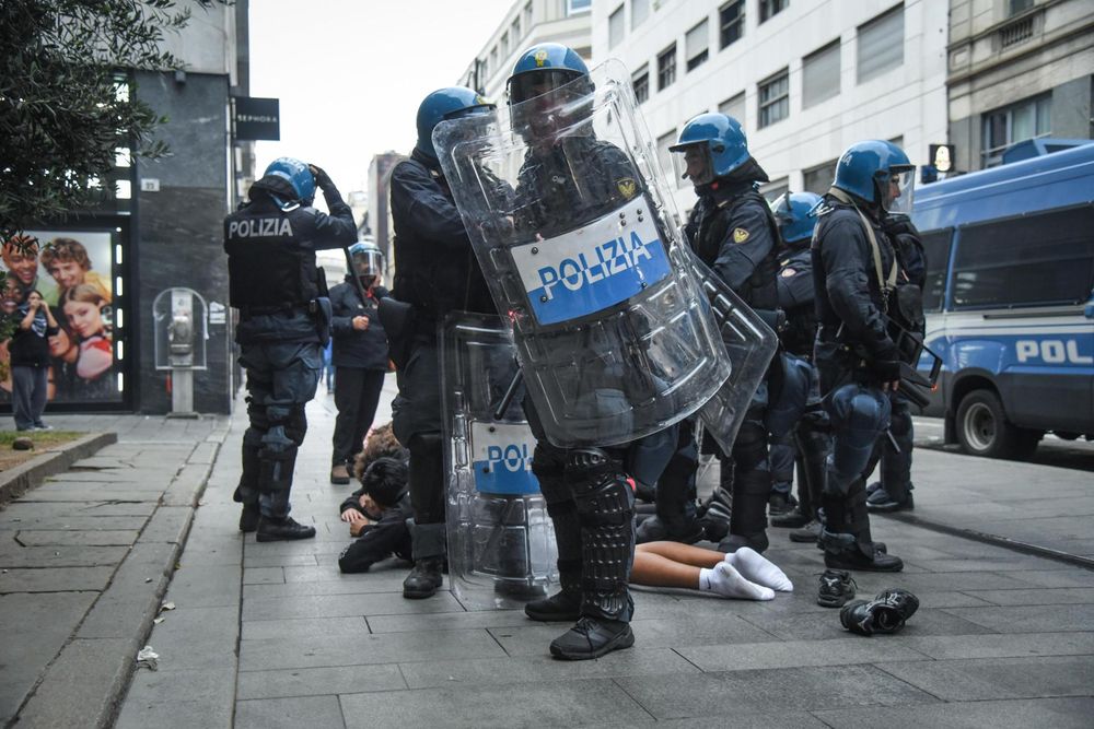 Agentes de la policía italiana con equipo antidisturbios rodean a una persona tendida en el pavimento durante los disturbios cerca de la Piazza del Duomo en Milán, Italia.