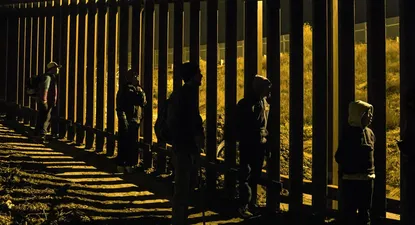 Migrantes en la frontera de Tijuana con Estados Unidos, el pasado sábado, mirando desde el lado mexicano a agentes de control del otro lado de la valla