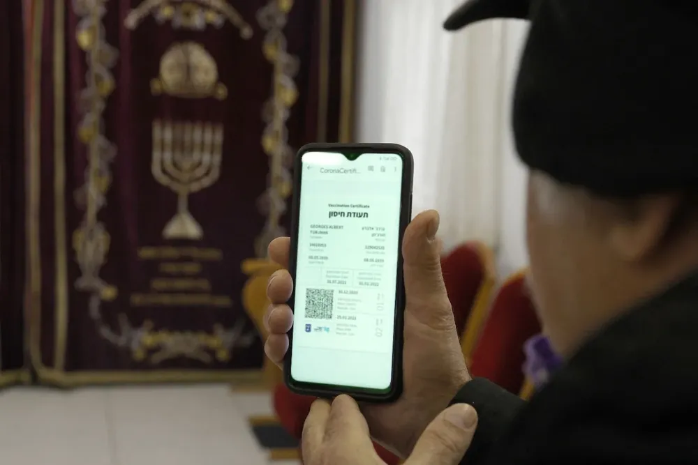 Un judío practicante muestra su pasaporte verde –que certifica que está vacunado contra el coronavirus– en una sinagoga de Isreael