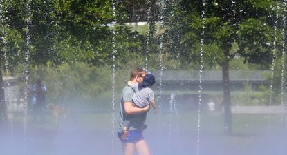 Un hombre con su hijo pasa por los chorros de agua de la playa de Madrid Río, a 24 de mayo de 2024, en Madrid.&nbsp;