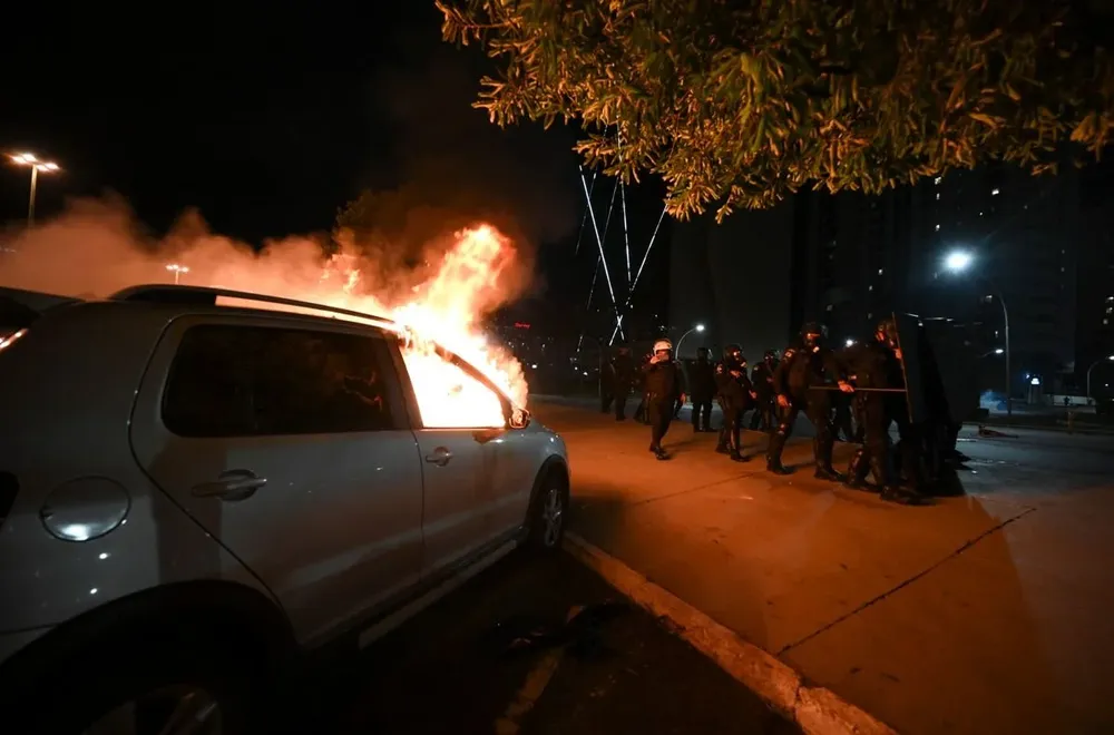 Policías junto a un auto prendido fuego por los disturbios causados por los bolsonaristas