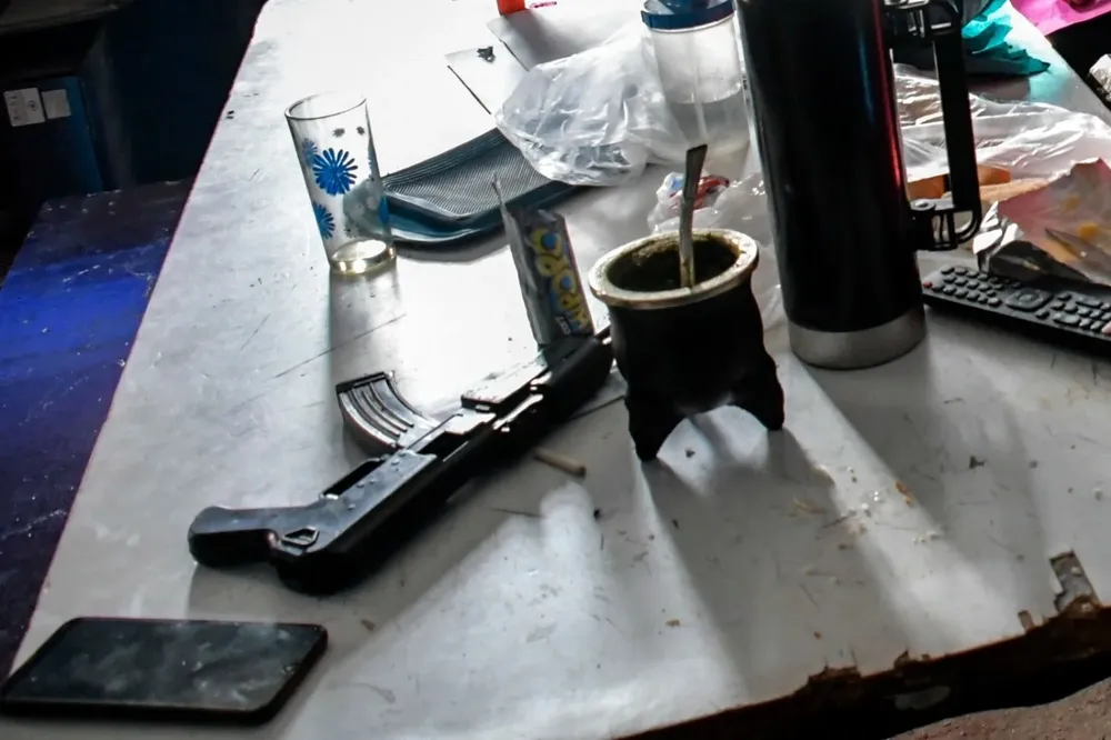 Un mate, galletitas y un subfusil en la cotidianidad de una mesa familiar.