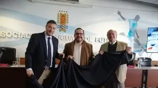 Romeo Volonté (SUL), Juan Ignacio Buffa (MGAP) y Fabio Montossi (INIA) muestran la tela con la que se confeccionarán los trajes.