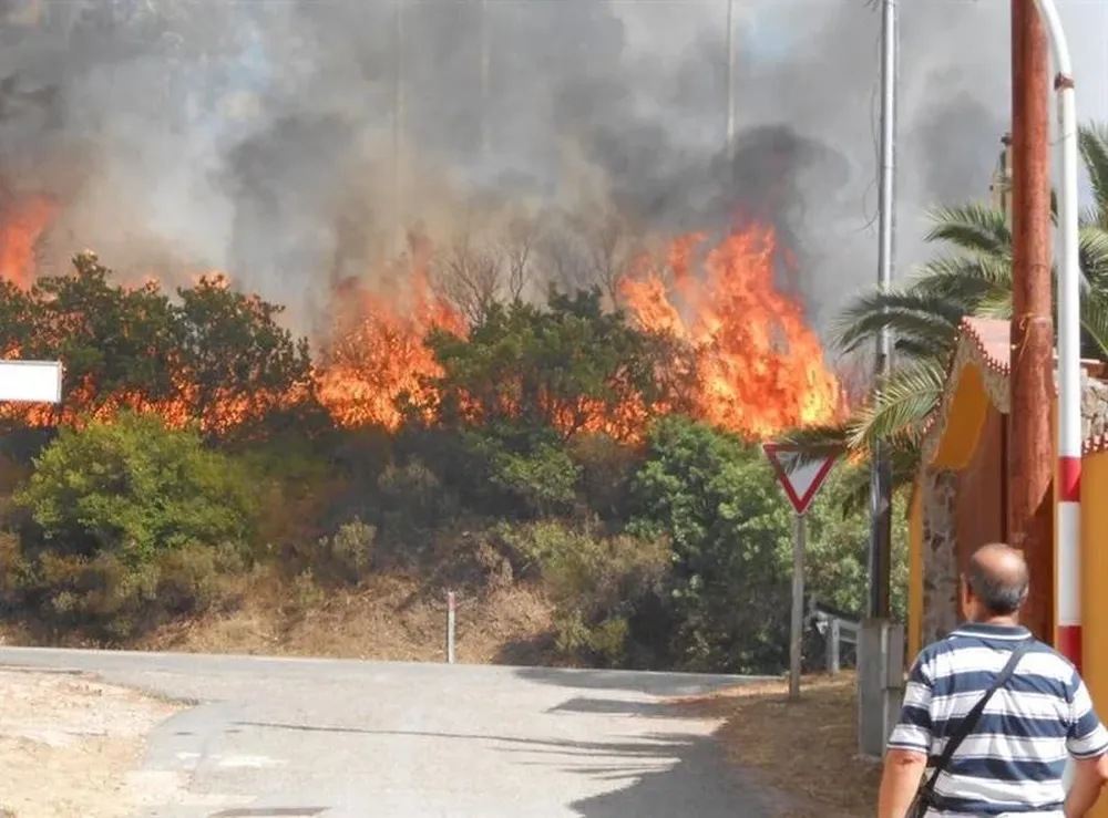 Un hombre observa las llamas de un incendio forestal en Cagliari en la región de Cerdeña