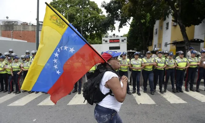 Una manifestante pasa con la bandera de Venezuela frente al cordón policial que dispuso el gobierno.