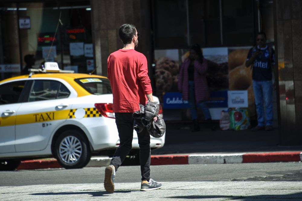 20240918 Gente caminando sin abrigo, un hombre caminando con la campera en la mano, primavera, estado del tiempo, buen tiempo.