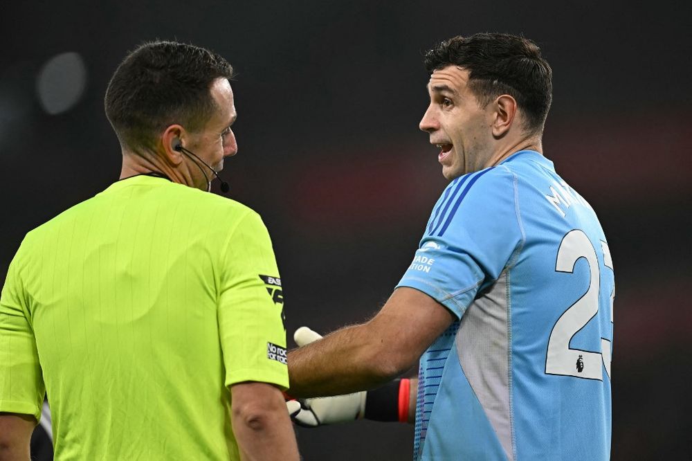 El juez David Coote y el golero argentino Dibu Martínez