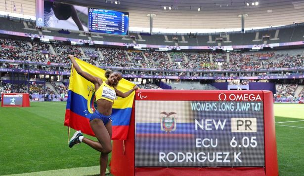 La atleta Kiara Rodríguez, de Ecuador, festeja junto a una pantalla que muestra su récord paralímpico en salto largo.