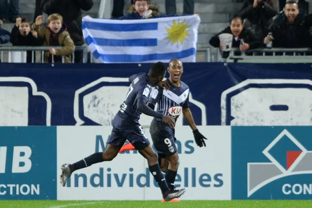Diego Rolan celebra con la bandera uruguaya de fondo