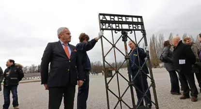 El ministro de educación y asuntos culturales de Bavaria, Ludwig Spaenle, frente a la puerta con el eslogan El trabajo los hará libres.