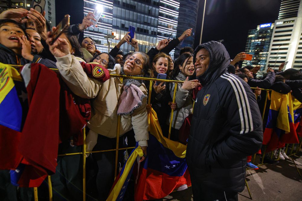 El jugador Wuilker Faríñez (d) se toma fotografías con los aficionados durante el recibimiento a la selección de fútbol de Venezuela este lunes, frente al Hotel Hilton Garden en Montevideo