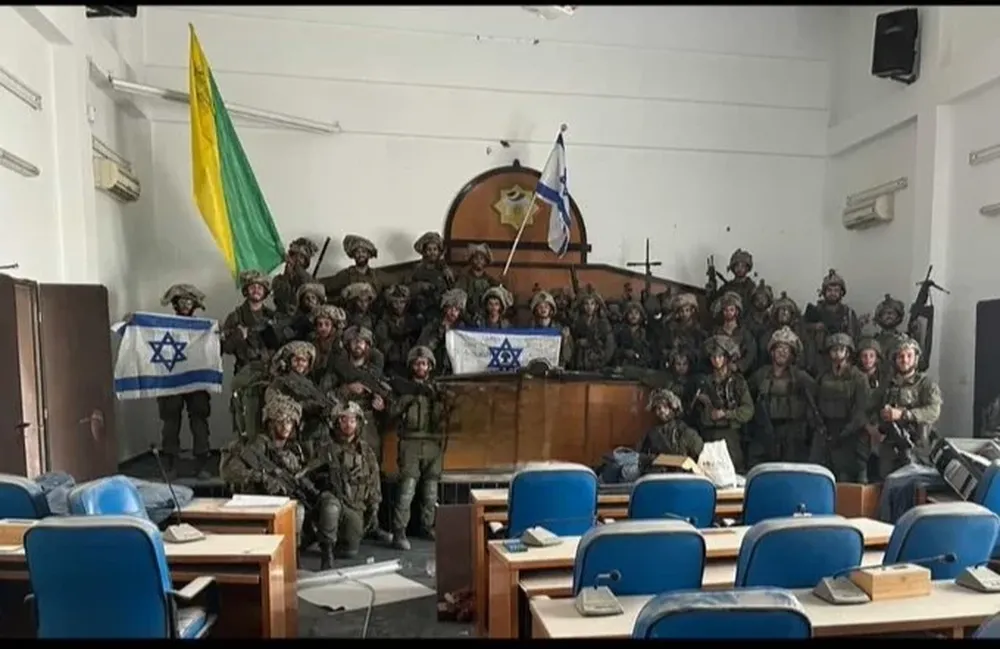 Miembros de la brigada de infantería Golani sostienen banderas de Israel dentro del edificio presuntamente capturado.