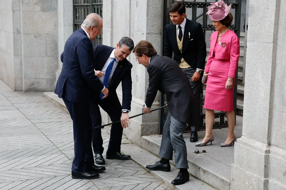 El alcalde de Madrid, José Luis Martínez-Almeida (c), recoge el bastón del rey emérito Juan Carlos I este sábado mientras lo recibe a las puertas de la iglesia de San Francisco de Borja de Madrid antes de contraer matrimonio con Teresa Urquijo.
