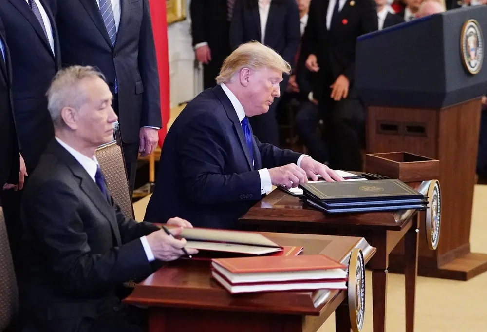 Donald Trump y el viceprimer ministro chino Liu He firmando el acuerdo.