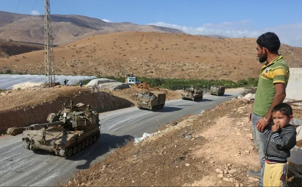 Un hombre y un niño miran al ejército israelí durante un ejercicio en los territorios en disputa.