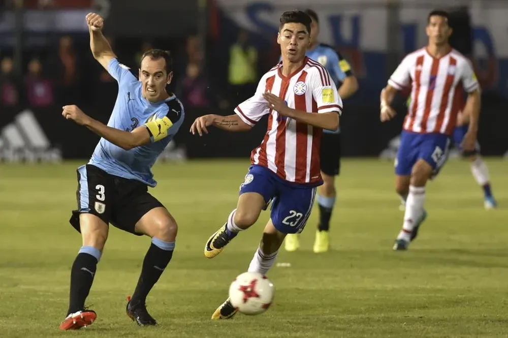 Diego Godín toca la pelota atrás ante la marca de Miguel Almirón