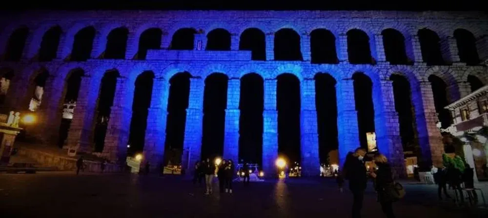 El Acueducto de Segovia se ha iluminado de color azul como muestra de apoyo a las personas con Trastorno del Espectro Autista (TEA) y sus familias en el Día Mundial de Concienciación sobre el autismo.  En un acto celebrado en la plaza del Azoguejo por la asociación Autismo Segovia, varias personas con trastorno del espectro autista han leído un manifiesto y el suelo de la plaza se ha iluminado con 600 velas formando el símbolo del infinito.  La iniciativa ‘Light it up blue’ (Ilumínalo en azul) consiguió que en el año 2023 se iluminasen 57 edificios y monumentos tanto de la capital de Segovia como de la provincia.  Según los datos de Autismo España, este trastorno tiene una prevalencia de aproximadamente un caso por cada 100 nacimientos, lo que implica que alrededor de 450.000 personas en España se encuentran dentro del espectro autista