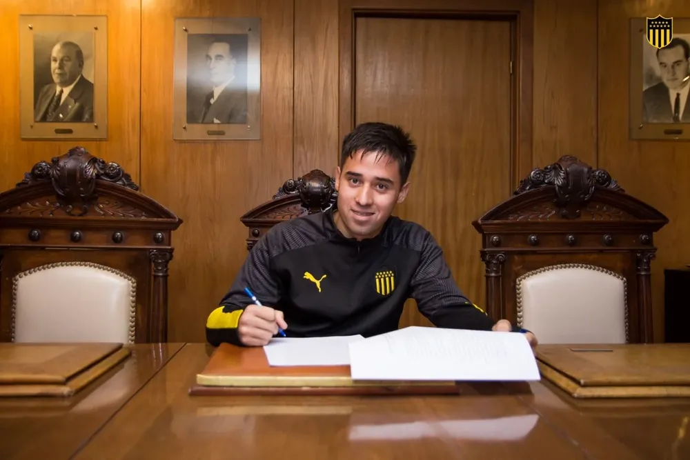 Óscar Cruz firmando contrato profesional en la sede de Peñarol