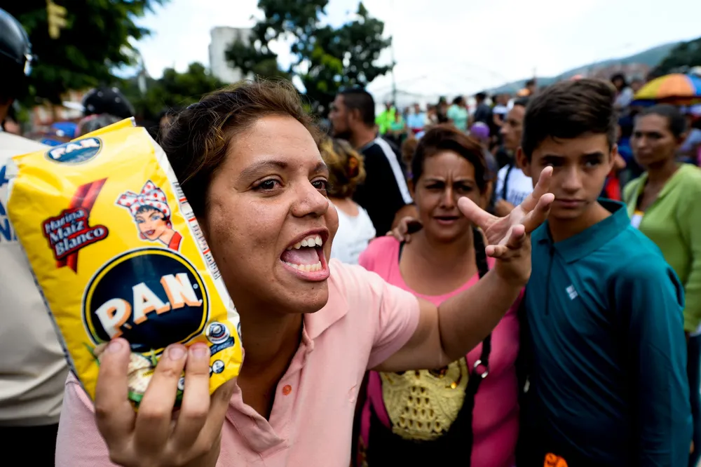 PA woman argues with members of the National Guard as she lines up to buy groceries in a supermarket at Catia neighborhood in Caracas, on June 11, 2016. Facing mounting pressure from food shortages, looting and increasingly violent protests, Venezuelan authorities on Friday announced the next stage of a recall referendum against embattled President Nicolas Maduro. / AFP / FEDERICO PARRA