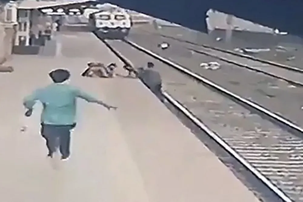 Fragmento del video en el que un hombre rescata a un niño que cae sobre las vías del tren en una estación de India