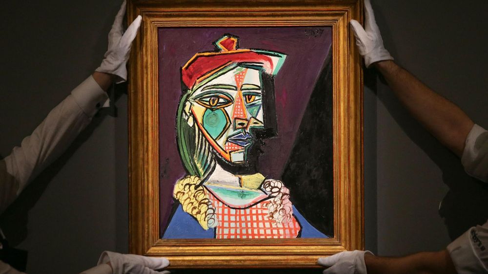 Asistentes de una galería sostienen una obra original del artista español Pablo Picasso.