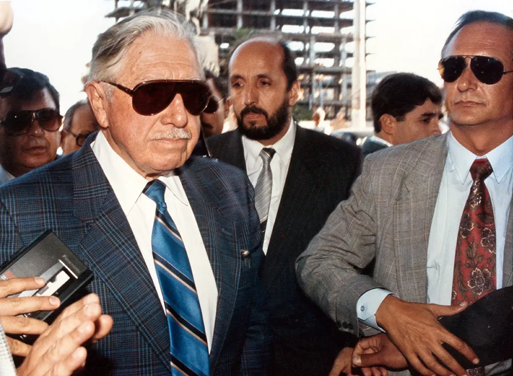 Casella, de lentes negros, a la izquierda de Pinochet en su visita a Uruguay en 1993