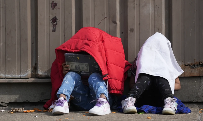 Niños se cubren la cabeza mientras están sentados afuera de un refugio para migrantes, el miércoles 13 de marzo de 2024, en Chicago.&nbsp;