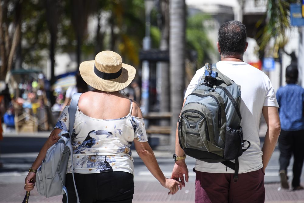20240201 Calor, verano, estado del tiempo. Una pareja caminando por Ciudad Vieja, una mujer con sombrero camina de la mano con un hombre.