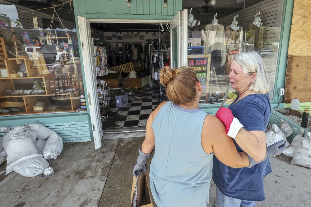 Madre e hija observan los da&ntilde;os causados a su tienda por la crecida del hurac&aacute;n Helene en Gulfport, Florida.