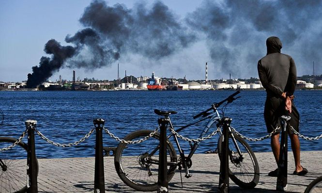 Un hombre observa la columna de humo que emana de la refinería Ñico López en La Habana.