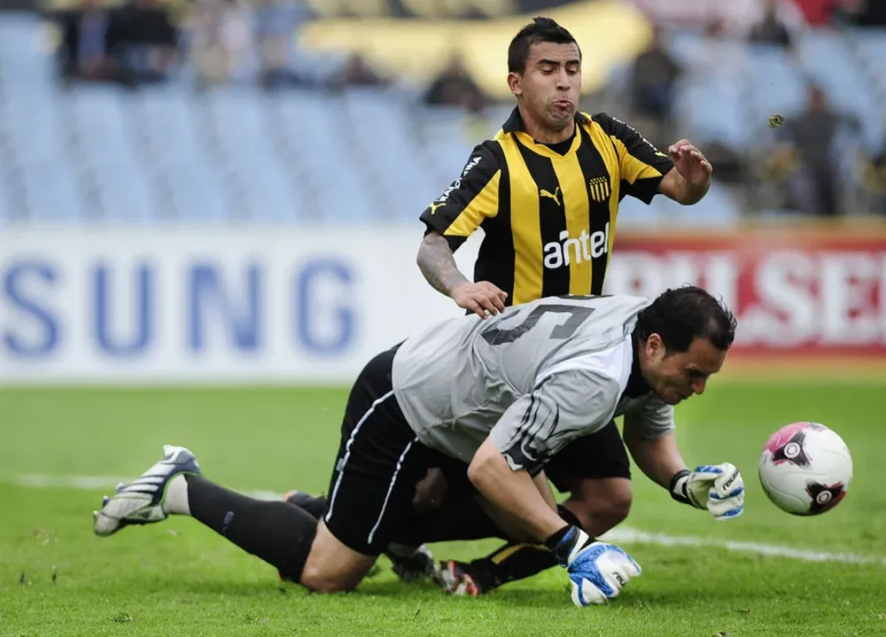 Nanni busca la pelota ante Zambrana en un partido entre Wanderers y Peñarol