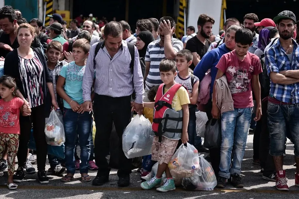 UN grupo de migrantes hace fila en Grecia, tras desembarcar desde el Mediterráneo y a la espera de seguir rumbo hacia Europa.