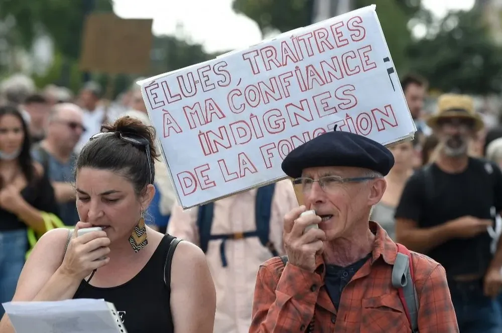Un hombre sostiene un cartel que dice Electos, traidores de mi confianza. Indigno del cargo durante una manifestación contra el pase de salud obligatorio Covid-19 para acceder a la mayor parte del espacio público, en Nantes.