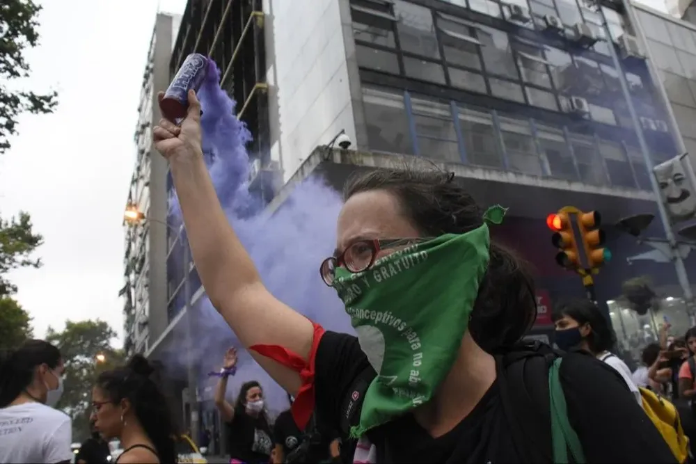 Una mujer deja salir humo violenta durante la marcha del 8 de marzo