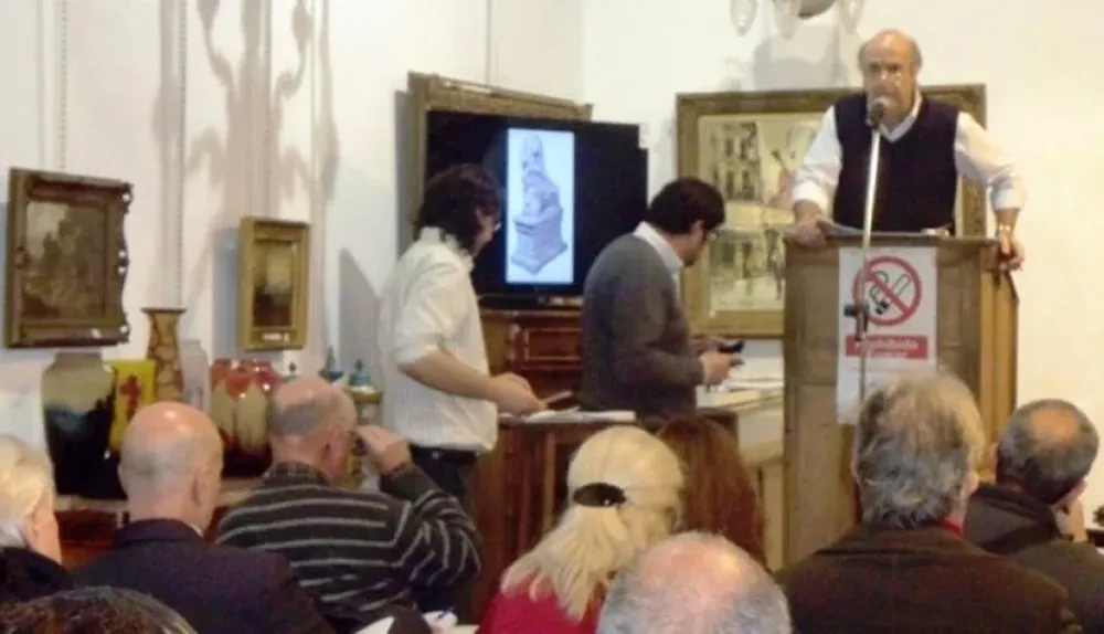 El rematador Héctor Bavastro subastando objetos de arte y antigüedades