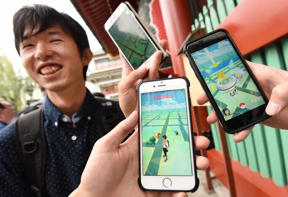 Estudiantes japoneses muestran sus celulares mientras juegan al Pokémon Go