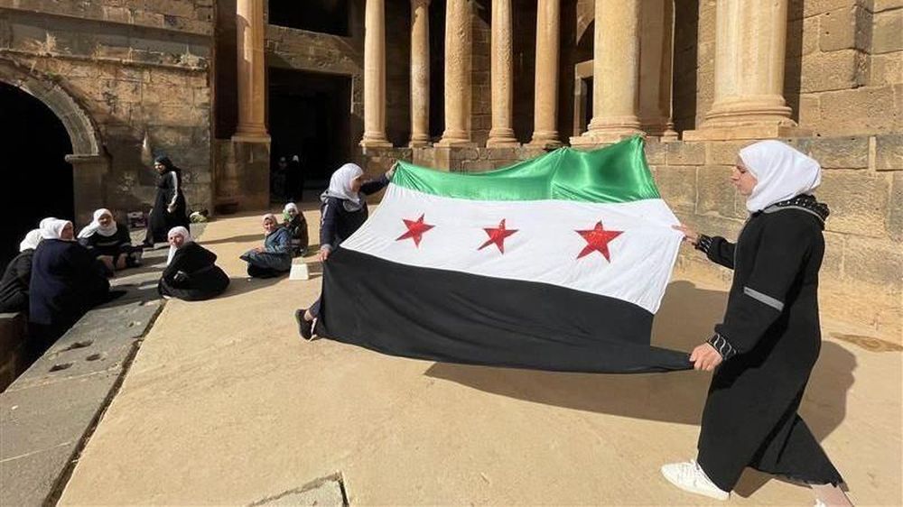 Las mujeres observan el despliegue de la nueva bandera siria, utilizada por la oposición.