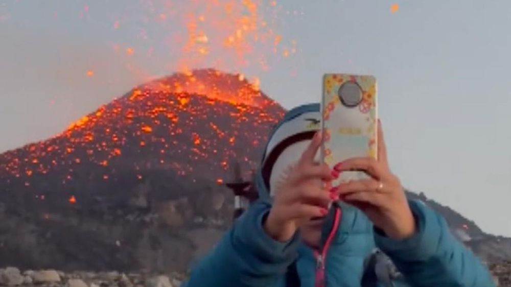 Una persona se toma una selfie frente al volcán Etna, Italia. 