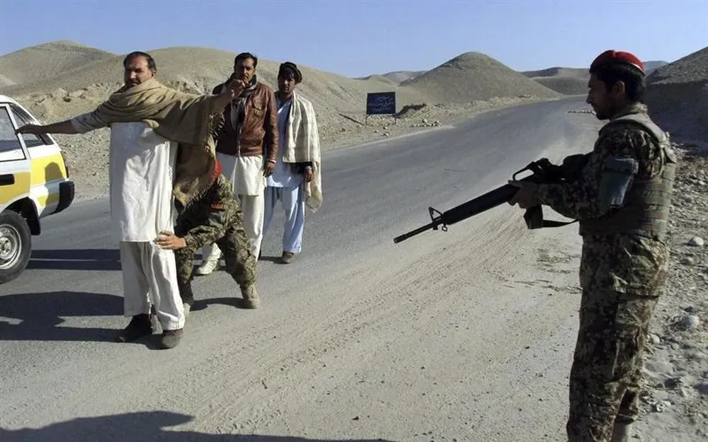 Soldados afganos cachean a varios hombre en un puesto de control de carreteras en la provincia de Laghman