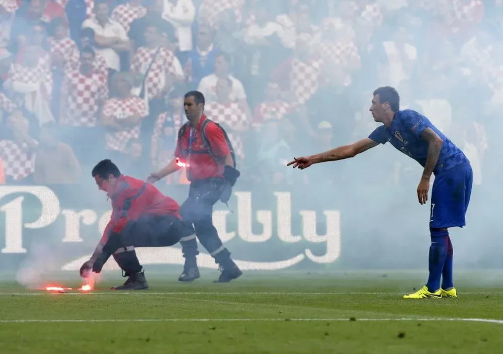 }Mandzukic le señala a unos bomberos que levanten las bengalas