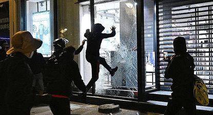 Varias personas rompen un escaparate el domingo en París.