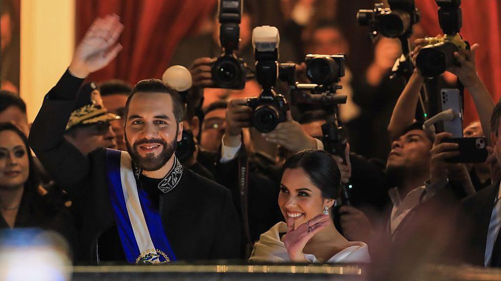 El presidente de El Salvador, Nayib Bukele, y su esposa, Gabriela Bukele, saludan a sus seguidores después de haberse dirigido a la ciudadanía con motivo de sus seis años al frente del gobierno.