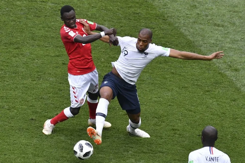 Pione Sisto, de Dinamarca, ante la marca del francés Djibril Sidibe