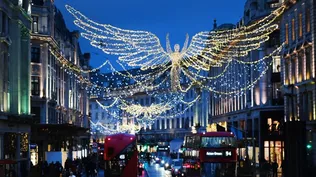 La gente y el tráfico suben por Regent Street debajo de las luces de Navidad en Londres, Gran Bretaña.