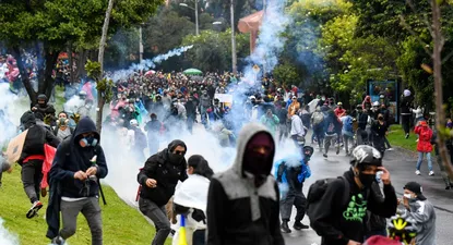 Manifestantes chocan con la policía antidisturbios durante una protesta contra un proyecto de reforma tributaria frente a la casa del presidente colombiano