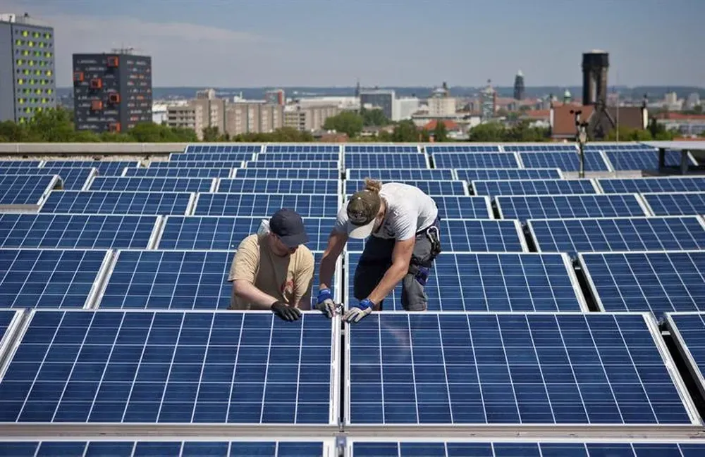 Alemania- Dos operarios instalan un panel solar en el techo de la universidad de Dresde