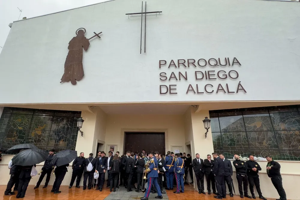 Costaleros, nazarenos y músicos se resguardan de la lluvia en la Iglesia de donde debería salir la Hermandad de El Sol en Sevilla.