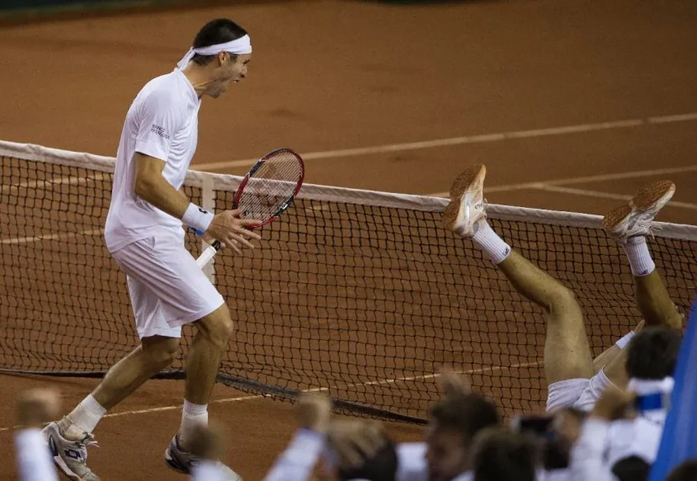 Leonardo Mayer, de pie celebra, con su compañero Carlos Berloq en el suelo, tras vencer Argentina a Serbia en dobles y clasificar a semifinales