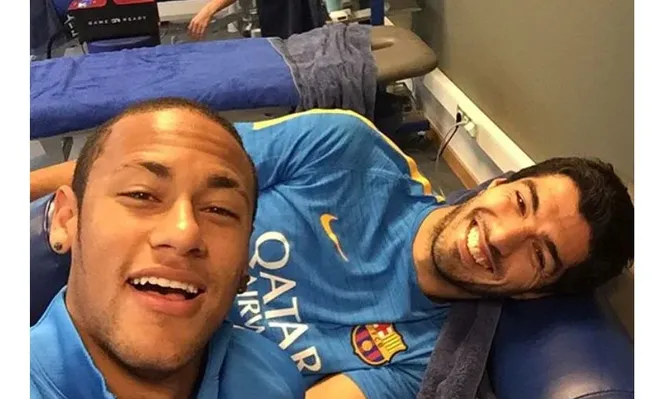 Neymar y Suárez sonríen; en el fondo, Messi se trata de su lesión